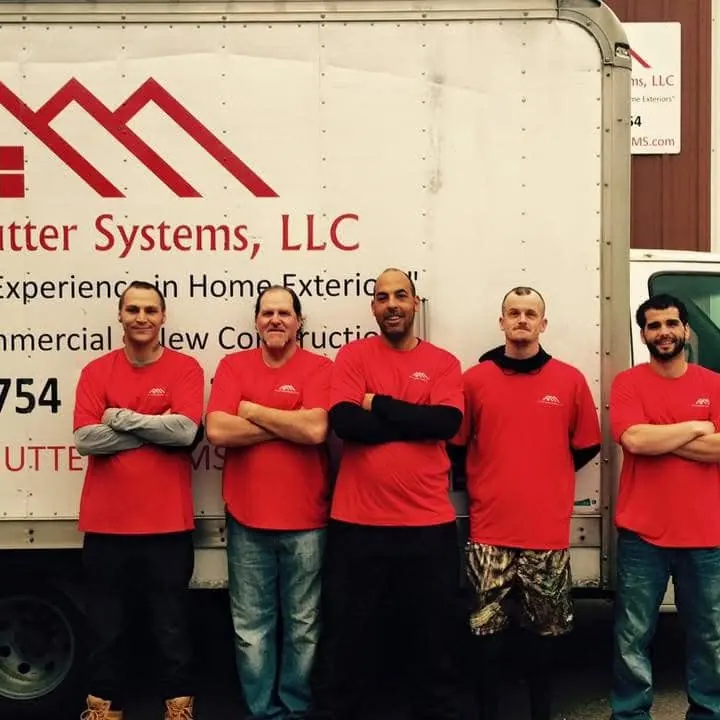 Five H&H crew members in red shirts standing in front of a company box truck