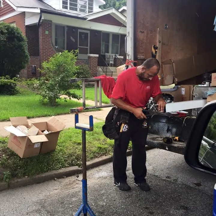 An H&H worker forming a gutter section beside a brick house