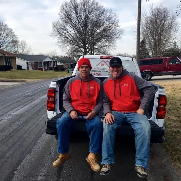 Two H&H crew members sitting on the tailgate of a company truck